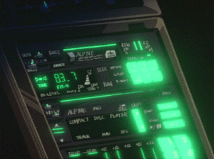 A tight camera shot of a cel animation GIF of a car stereo in a dark car interior. The numbers and buttons glow bright green as they flicker and change